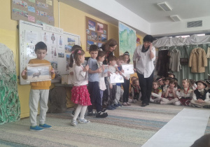 Kilkoro dzieci stoi z ilustracjami zwierząt i roślin