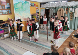 Dziewczynki i chłopcy stoją w parach w strojach góralskich