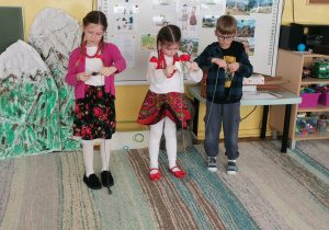 Troje dzieci nawija włóczkę na sylwetę owieczki