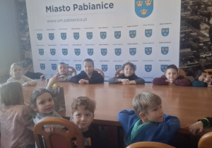 Dzieci siedzą w sali obrad