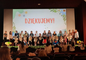 Dzieci biorące udział w przeglądzie, z nauczycielkami z nagrodami i dyplomami