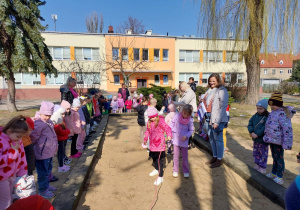 Kilkoro dzieci łowi papierowe rybki w piaskownicy