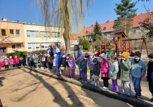 Kilkoro dzieci łowi papierowe rybki w piaskownicy