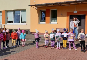 Kilkoro dzieci trzyma ilustracje zwierząt i ich ślady