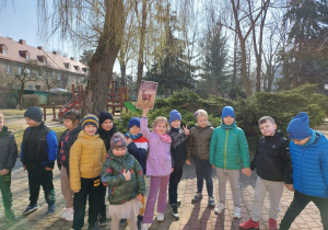 Kilkoro dzieci stoi, a jedna dziewczynka trzyma zdjęcie jelonka