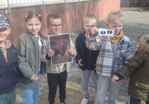 Klkoro dzieci stoi, a dwoje z nich trzyma zdjęcia - żubra i jego ślady