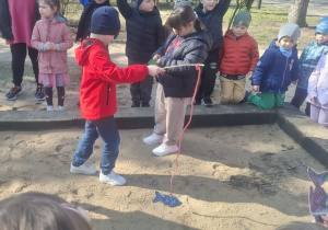 Chłopiec łowi sylwetę ryby w piaskownicy