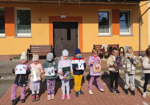 Kilkoro dzieci trzyma zdjęcia zwierząt i ich ślady