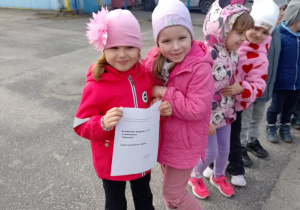 Dwie dziewczynki trzymają kartkę z wagą grupy