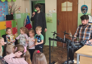 Kilkoro dzieci gra na instrumentach perkusyjnych a muzyk na perkusji