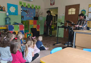 Dzieci słuchają, jak muzyk gra na perkusji