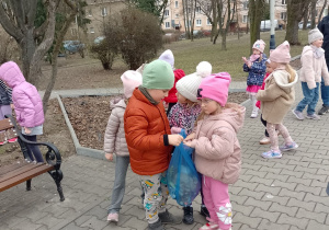 Troje dzieci trzyma worek z odpadami