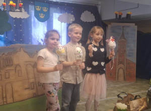 Troje dzieci pokazuje swoje pisanki