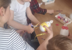 Dziewczynka z mamą przy stoliku ozdabia jajko