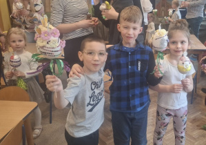 Dwóch chłopców i jedna dziewczynka trzymają w rękach pisanki