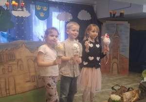 Troje dzieci pokazuje swoje pisanki