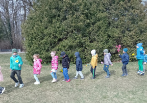 Dzieci idą gęsiego z kwiatami w dłoniach