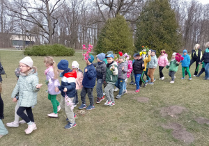 Dzieci idą w parach z kwiatami w dloniach