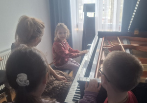Dziewczynka z nauczycielką szkoły siedzi przy fortepiania