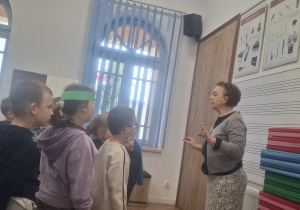 Nauczycielka szkoły z batutą w ręku stoi przed dziećmi