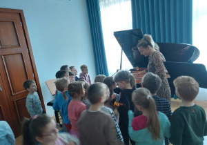 Nauczycielka pokazuje dzieciom fortepian