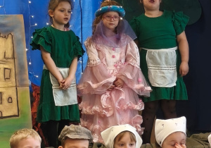 Trzy dziewczynki w strojach podczas przedstawienia na scenie