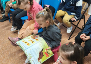 Dziewczynka ogląda książkę z cyklem rozwoju roślin