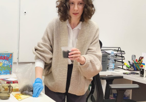 Pani biblotekarka trzyma pojemniczek z ziemią