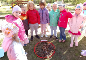 kilkoro dzieci stoi przy ułozonym ogródku w obręczy