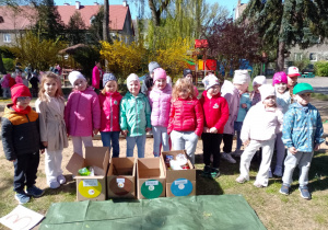 Dzieci stoją przy pudełkach z posegregowanymi śmieciami