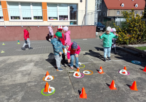 Dzieci rzucają obręczami na pachołki