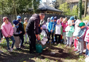 Dzieci patrzą, jak pan Jarek podlewa drzewko