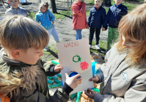 Dwoje dzieci stawia stempelek na kartonie