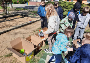 Dzieci segregują śmieci do oznakowanych pudełek