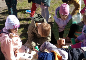 Kilkoro dzieci tworzy drzewa z rolek po papierze