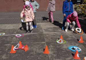 Dzieci rzucają obręczami na pachołki