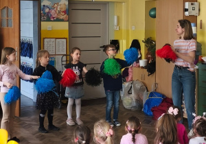 Kilkoro dzieci tańczy z pomponami