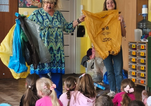 Dwie panie prowadzące pokazują worki do segregacji odpadów