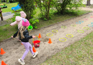 Dwie dziewczynk ipokonują slalom z wiaderkami