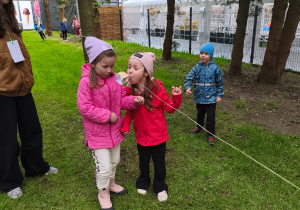 Dwie dziewczynki dmuchają w domek na lince