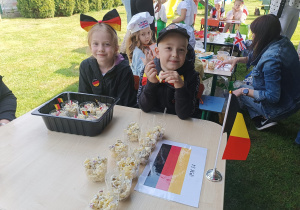 Dzieci siedzą przy stoliku, na którym stoi sałatka