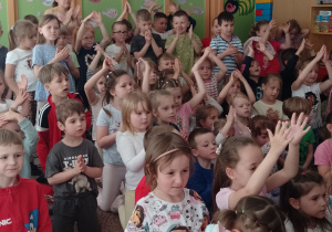 Dzieci siedzą i klaszczą podczas koncertu