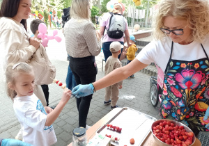 Pani Wiesia podaje dziewczynce owocowego szaszłyka