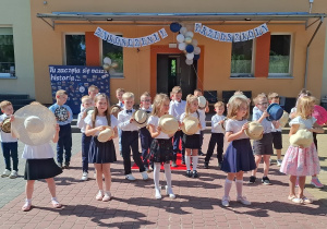Dzieci trzymają kapelusze podczas śpiewania piosenki
