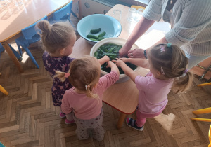 Troje dzieci myje ogórki w misce