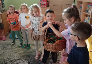 Dzieci w kole podają sobie jesienny kosz