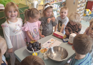 Dzieci stoją przy stoliku z produktami na ciasto