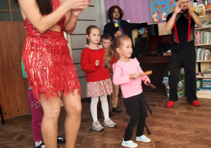 Dziewczynka gra na instrumencie, tancerze klaszczą