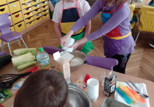 Dwie dziewczynki wsypują mąkę do miski