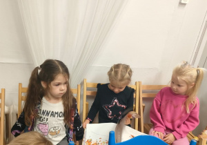 Trzy dziewczynki oglądają książkę